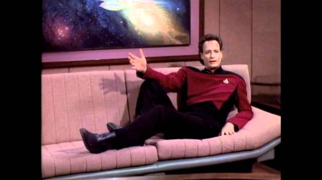 Q reclining on a couch in the pose of making another ridiculous protestation of innocence.
