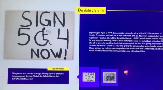 Close up of the screen — at National Museum of American History. Under the 504 graphic, caption: "This poster was carried during a 25-day sit-in to promote the passage of Section 504 of the Rehabilitation Act. Gift of Kenneth E. Stein" — at National Museum of American History. Under the 504 graphic, caption: "This poster was carried during a 25-day sit-in to promote the passage of Section 504 of the Rehabilitation Act. Gift of Kenneth E. Stein" — at National Museum of American History. Under the 504 graphic, caption: "This poster was carried during a 25-day sit-in to promote the passage of Section 504 of the Rehabilitation Act. Gift of Kenneth E. Stein" — at National Museum of American History. Under the 504 graphic, caption: "This poster was carried during a 25-day sit-in to promote the passage of Section 504 of the Rehabilitation Act. Gift of Kenneth E. Stein" — at National Museum of American History. Under the 504 graphic, caption: "This poster was carried during a 25-day sit-in to promote the passage of Section 504 of the Rehabilitation Act. Gift of Kenneth E. Stein" — at National Museum of American History. Under the 504 graphic, caption: "This poster was carried during a 25-day sit-in to promote the passage of Section 504 of the Rehabilitation Act. Gift of Kenneth E. Stein" — at National Museum of American History.