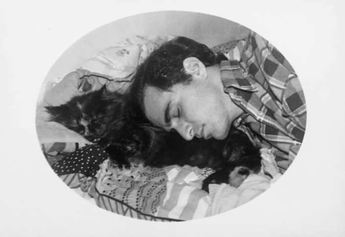 B/W photo of a young white man sleeping peacefully with a calico kitty